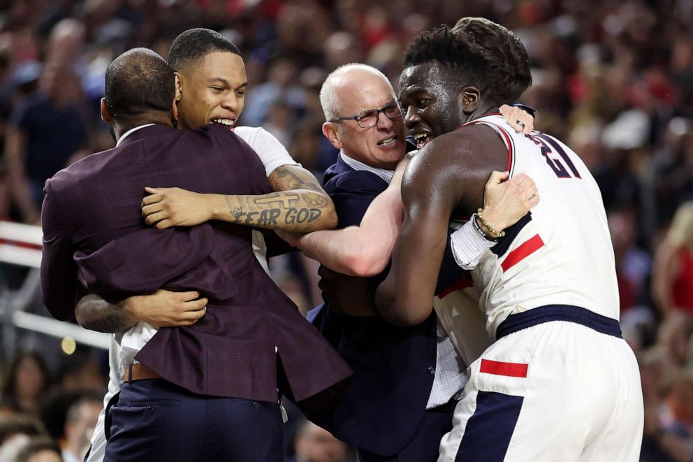 PHOTO: Adama Sanogo #21 and Jordan Hawkins #24 of the Connecticut Huskies celebrate with head coach Dan Hurley during the NCAA Men's Basketball Tournament National Championship game at NRG Stadium, April 03, 2023 in Houston.