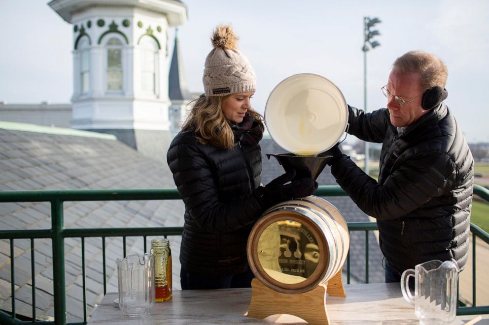 PHOTO: Assistant master distiller Elizabeth McCall and master distiller Chris Morris add local honey to a barrel that ages inside the Twin Spires for 145 days at Churchill Downs.