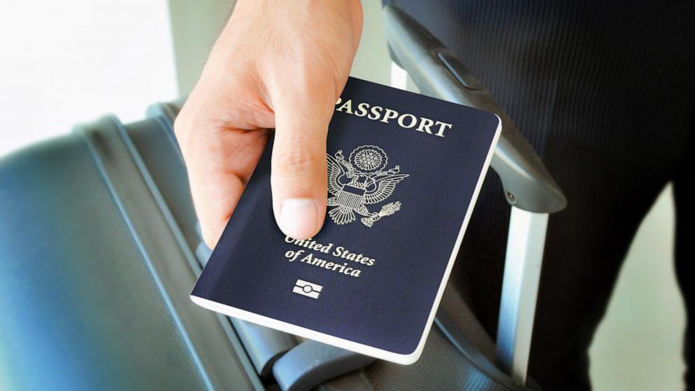 PHOTO: A hand holding a U.S. passport over a luggage.