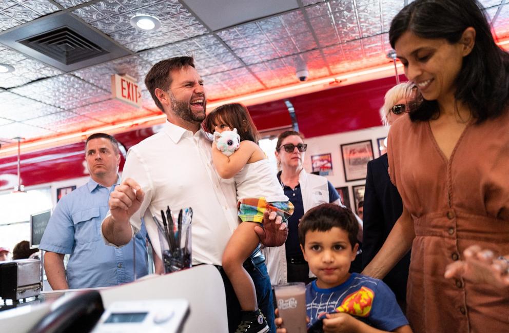 PHOTO: Republican vice presidential nominee Sen. J.D. Vance carries his daughter Maribel Vance as he arrives with wife Usha Vance to greet supporters at the Park Diner, July 28, 2024, in St Cloud, Minn.