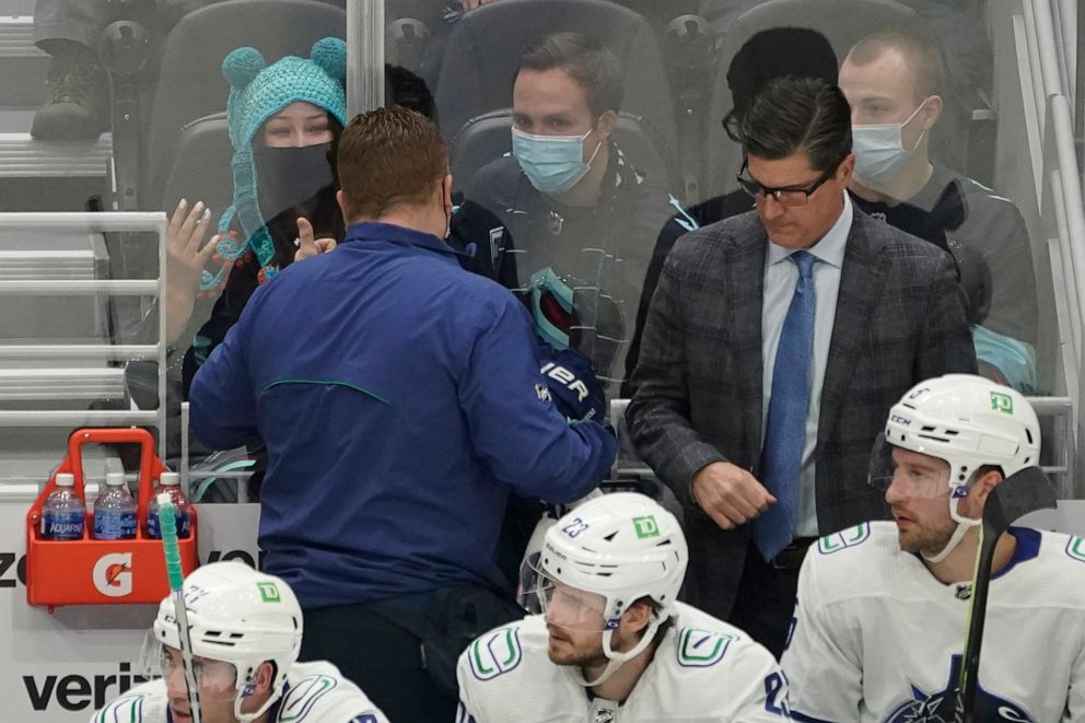 PHOTO: Nadia Popovici, upper left, gestures toward Brian "Red" Hamilton, second from left, after they were introduced during an NHL hockey game, Jan. 1, 2022, in Seattle. Popovici alerted Hamilton at a previous, Oct. 23, 2021 game of a cancerous mole. 