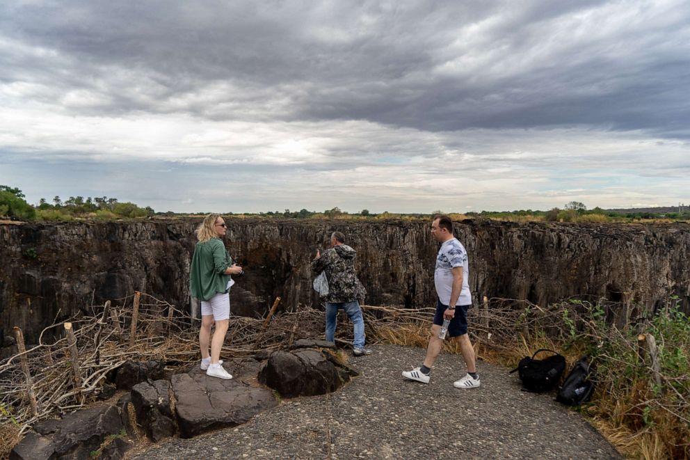 PHOTO: Tourists view the majestic Victoria Falls, with a larger part of it without the flowing blanket of water due to a drought in the region, Victoria Falls, Zimbabwe, Nov. 13, 2019.