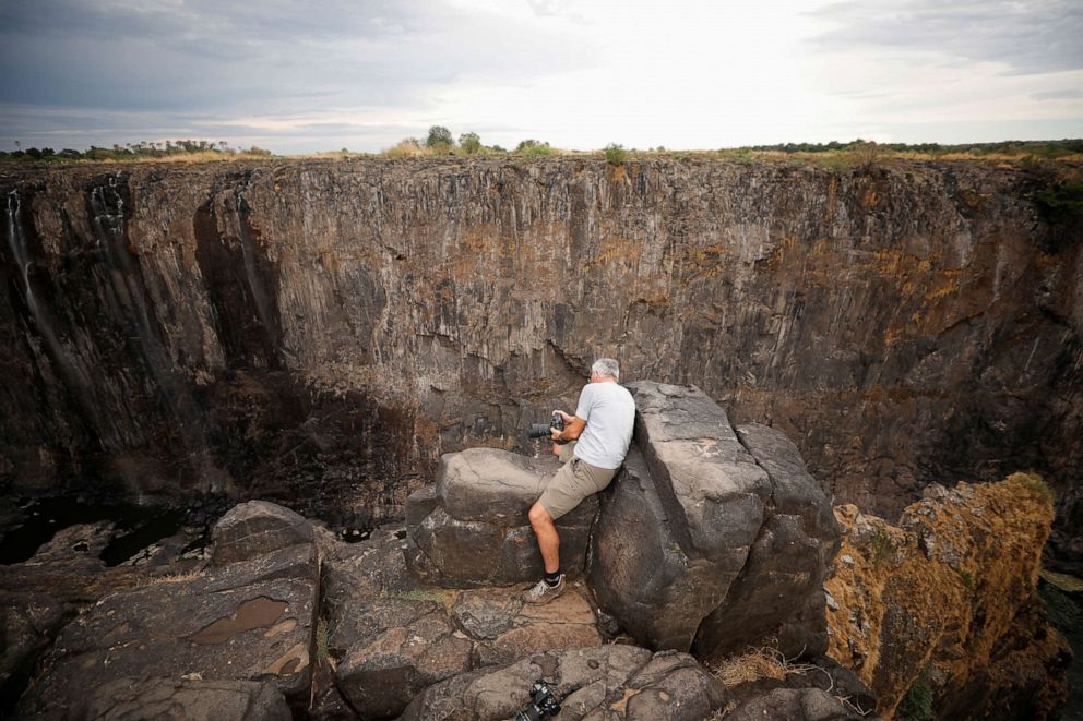 PHOTO: Visitors take pictures before dry cliffs following a prolonged drought at Victoria Falls, Zimbabwe, Dec. 4, 2019.