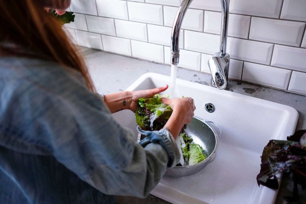PHOTO: A woman washes produce in a sink in this stock photo.