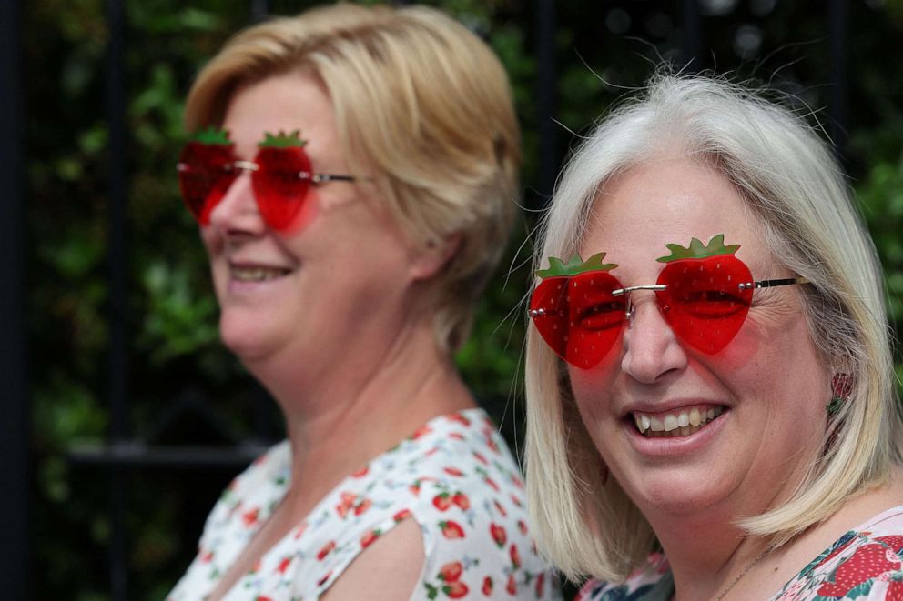 PHOTO: Two women sporting strawberry-shaped glasses smile while waiting in line to enter on the first day of the 2023 Wimbledon Championships in London, July 3, 2023.