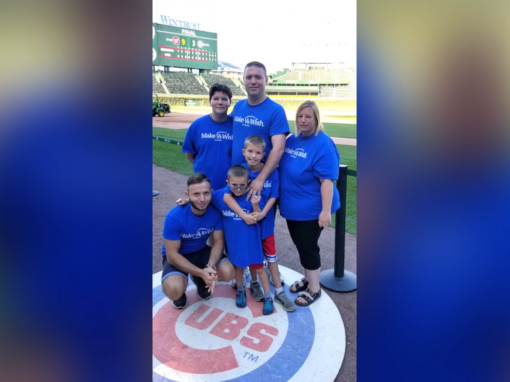 PHOTO: Dennis Gutt, kneeling, attends a Chicago Cubs game with Gabriel Smith and his family.