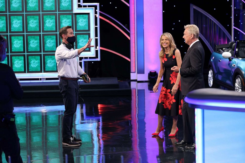 PHOTO: Pat Sajak and Vanna White talk with a masked contestant on the set of "Wheel of Fortune."