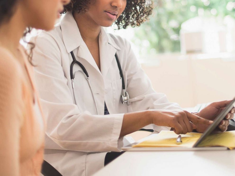 PHOTO: A woman looks over documents with her doctor in an undated stock photo.