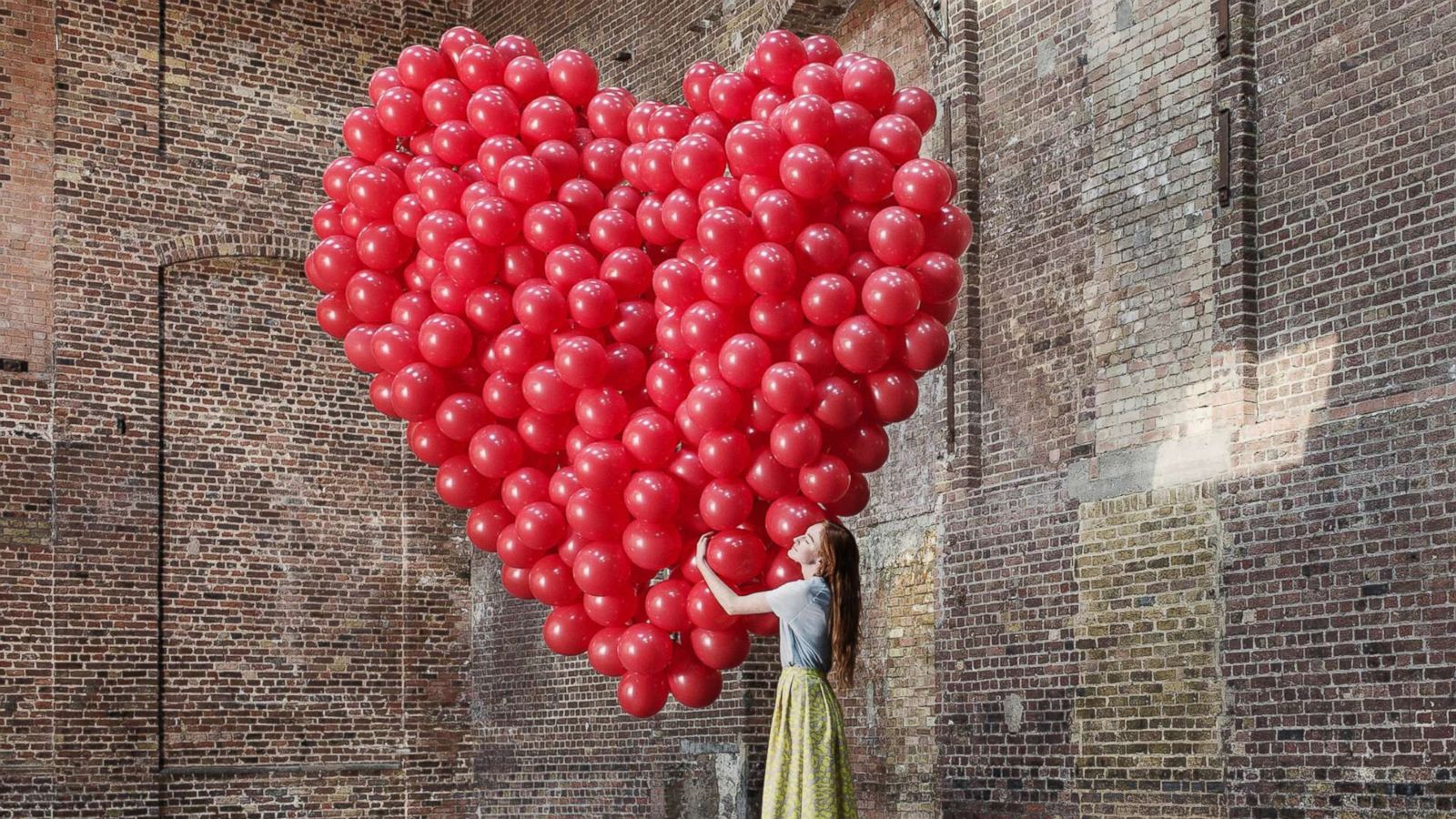 PHOTO: A woman hugs a bunch of balloons shaped like a heart in an undated stock photo.