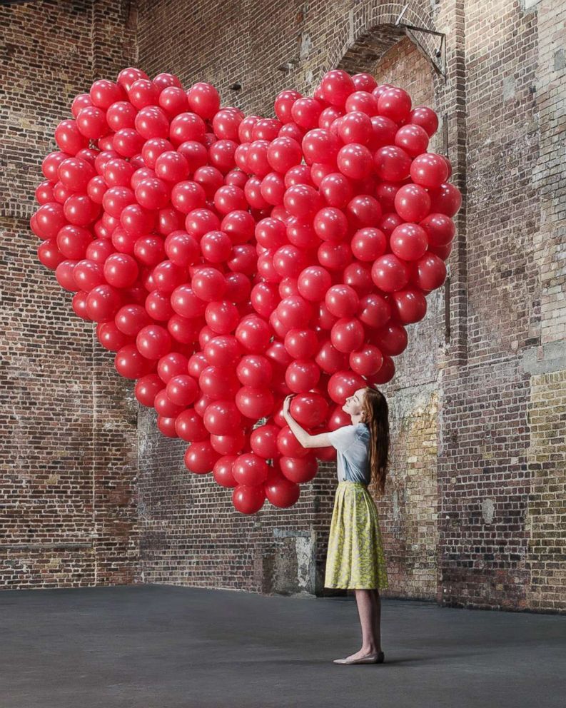 PHOTO: A woman hugs a bunch of balloons shaped like a heart in an undated stock photo.