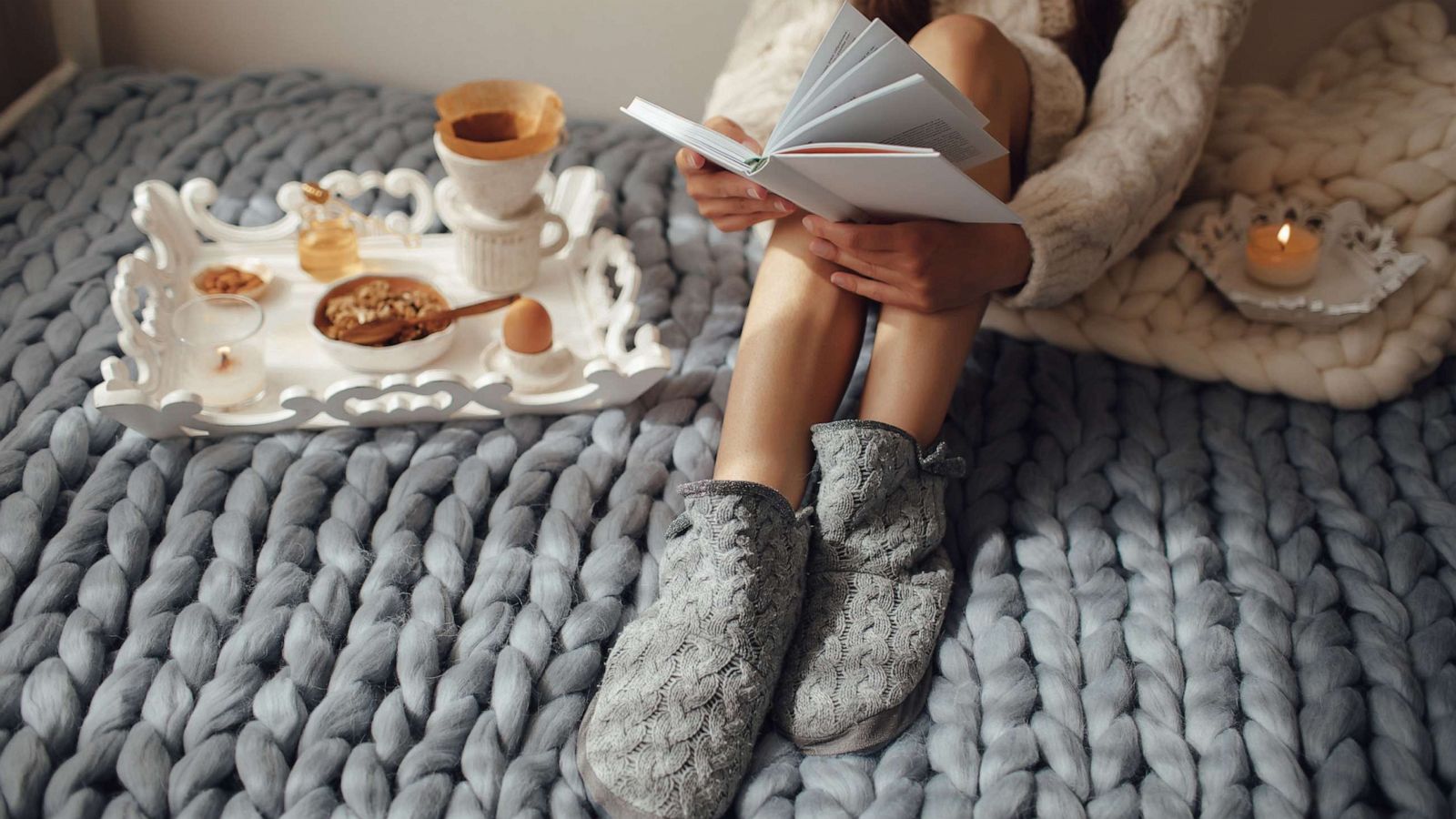 PHOTO: Woman with long hair drinking hot coffee and reading book in bed.