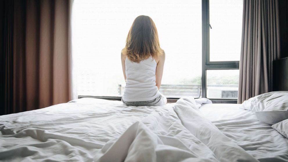 PHOTO: A women sits on a bed in this undated stock photo.