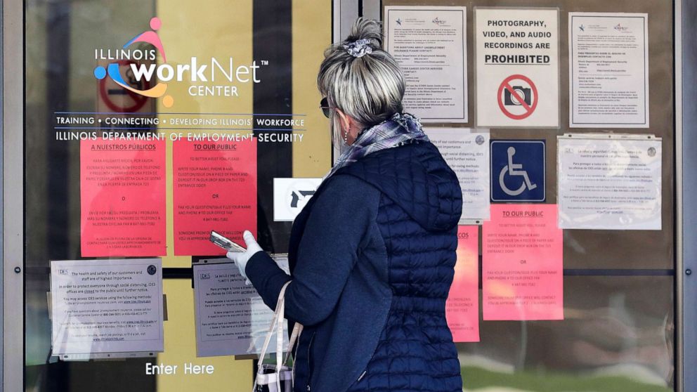 PHOTO: A woman checks job application information in front of IDES(Illinois Department of Employment Security)/WorkNet center in Arlington Heights, Ill., April 9, 2020.