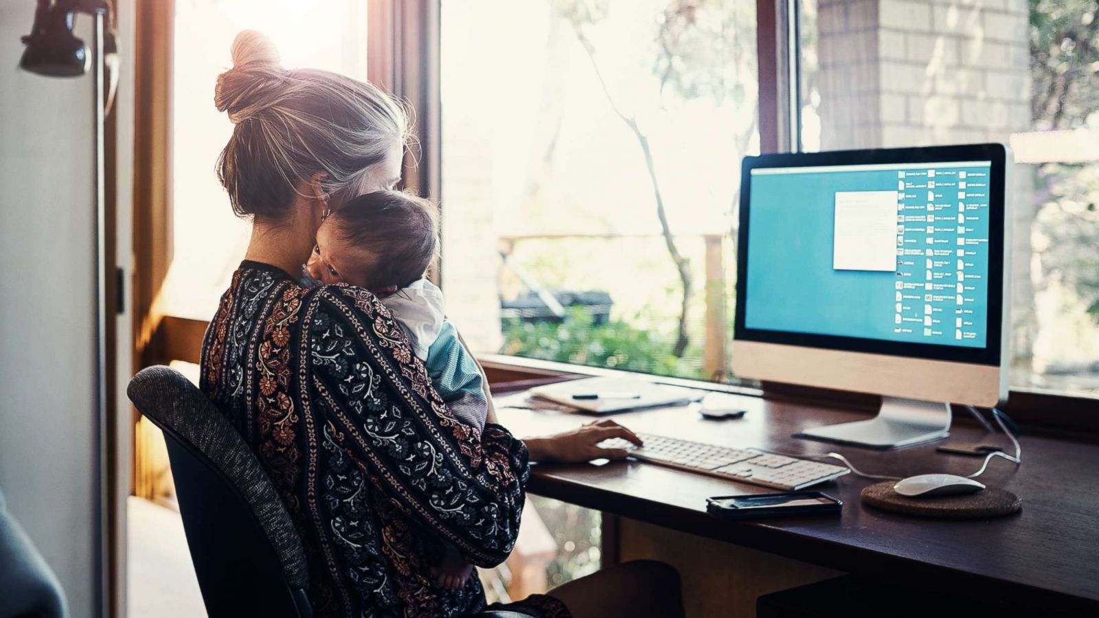 PHOTO: A working mom holds her child in this stock photo.