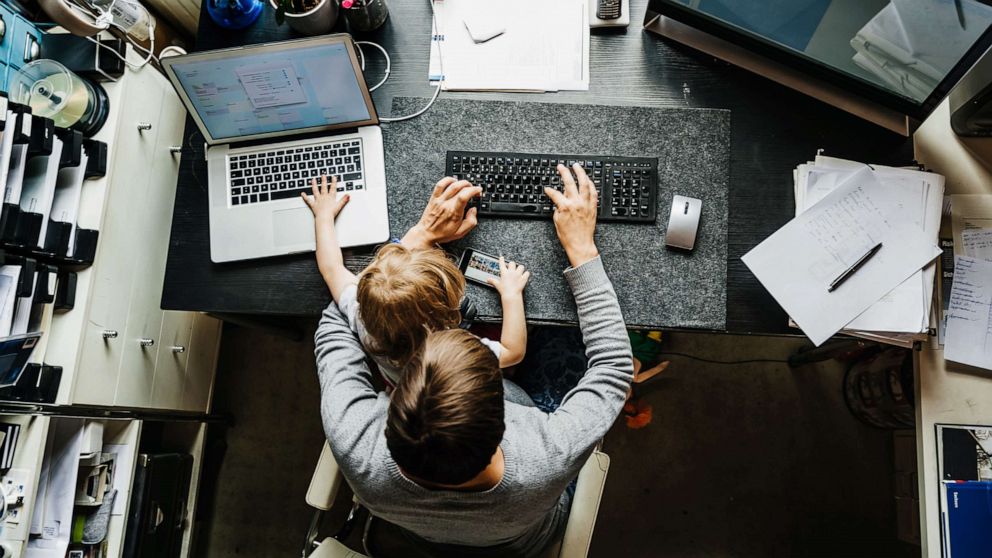 PHOTO: An undated stock photo depicts a mother working in a home office with a child on her lap.