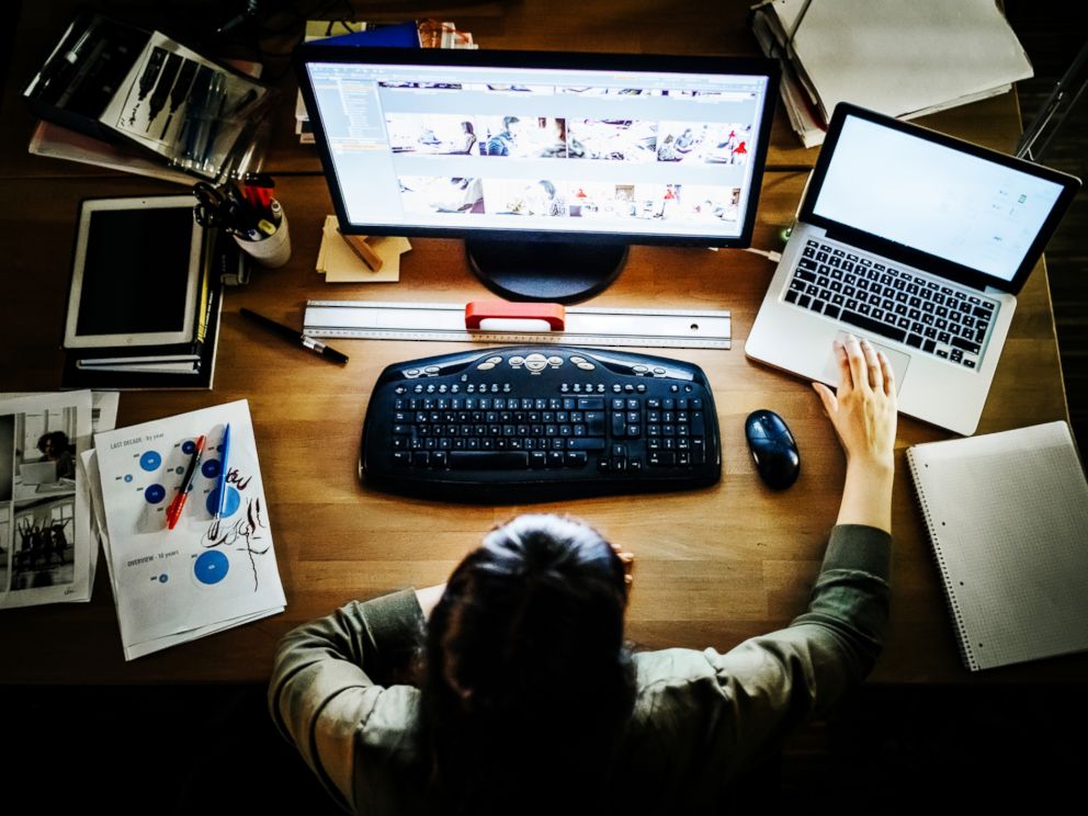 PHOTO: A businesswoman working late on a computer and laptop in a modern office space in this undated stock photo.