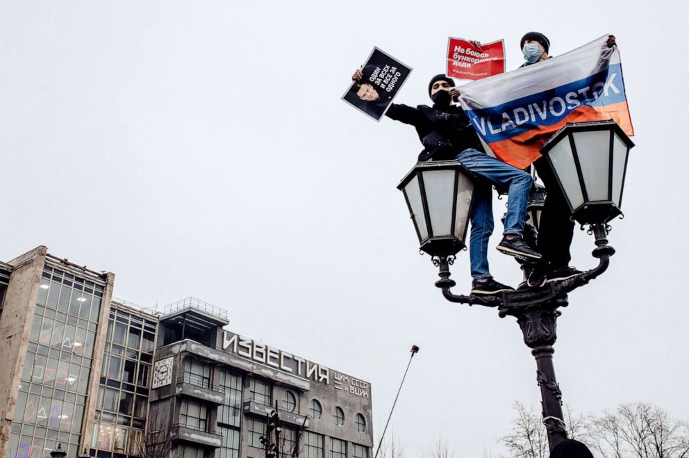 PHOTO: Young protesters hold banners as climnb atop a lamppost in Pushkin Square, Moscow,  Jan. 23, 2021.