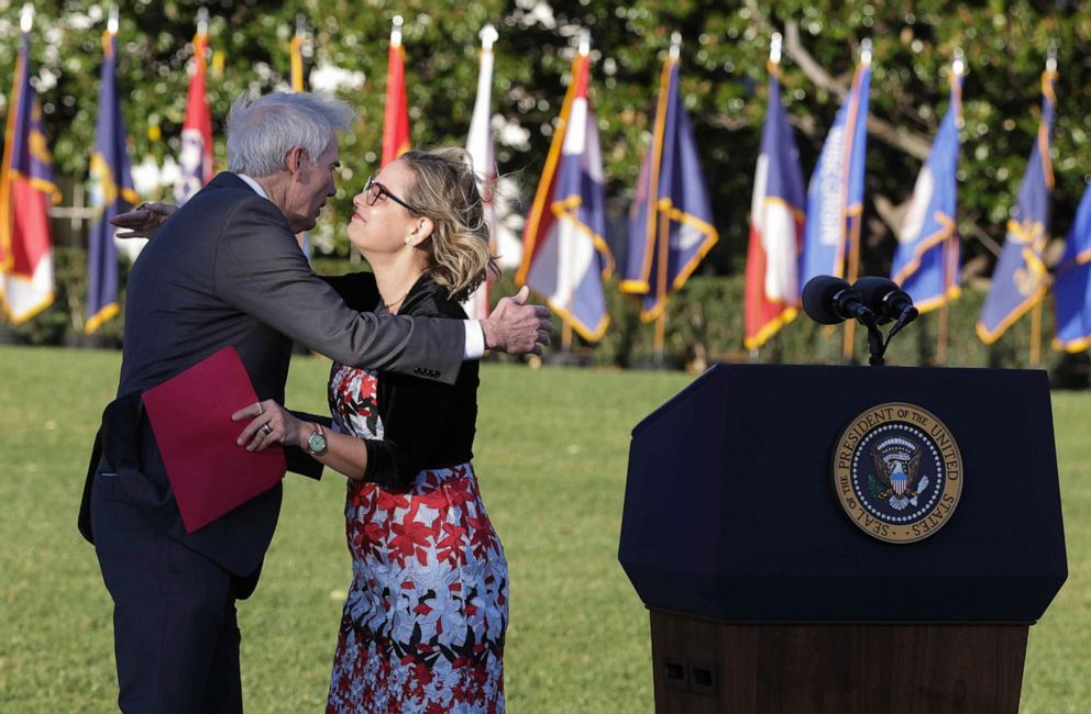 PHOTO: Sen. Kyrsten Sinema hugs Sen. Rob Portman after delivering remarks before President Joe Biden signed the Infrastructure Investment and Jobs Act during a ceremony on the South Lawn at the White House on Nov. 15, 2021.