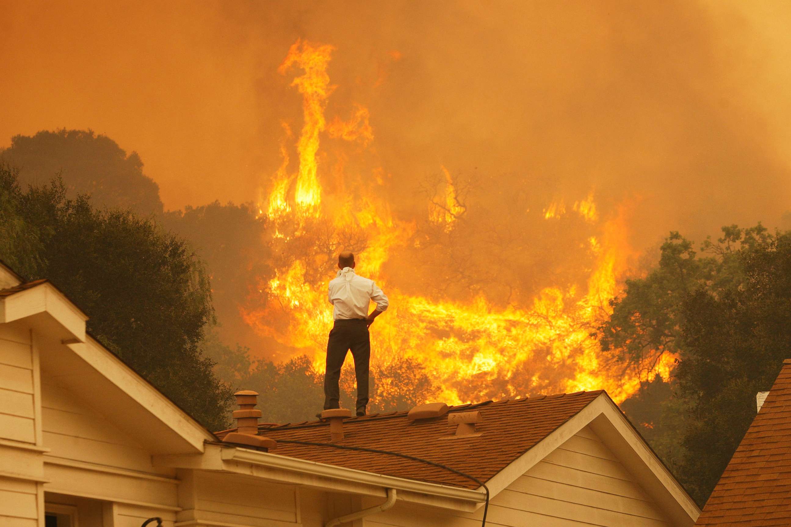 PHOTO: A man standing on a rooftop looks at approaching flames as the Springs fire continues to grow  near Camarillo, Calif., May 3, 2013. 