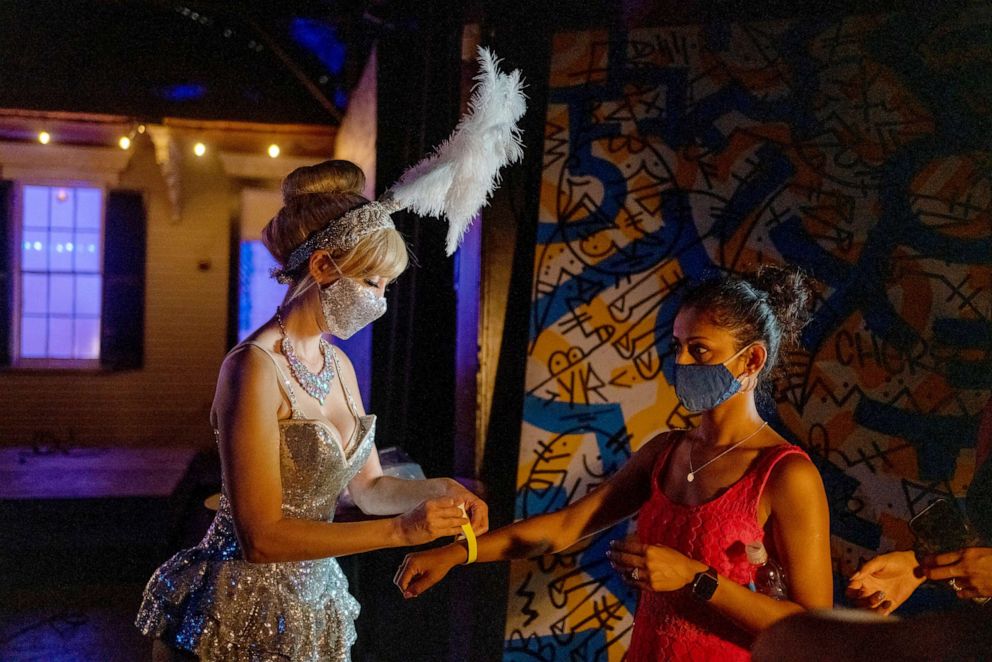 PHOTO: Producer and burlesque dancer Trixie Minx hands out masks to audience members, having asked both the attendees and performers to mask up before the  performance as Louisiana rises to worst COVID-19 outbreak in U.S. in New Orleans, July 25, 2021.