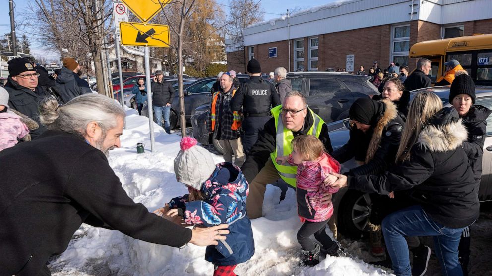 PHOTO: Parents and their children are loaded onto a warming bus as they wait for news after a bus crashed into a daycare center in Laval, Quebec, Feb. 8, 2023.