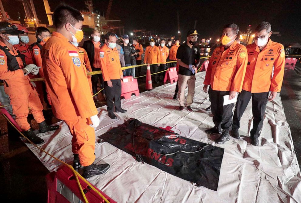 PHOTO:Members of the National Search and Rescue Agency Bagus Puruhito examine a body bag containing debris found in the water off Java Island, Jakarta, Indonesia, early Sunday, Jan. 10, 2021. 