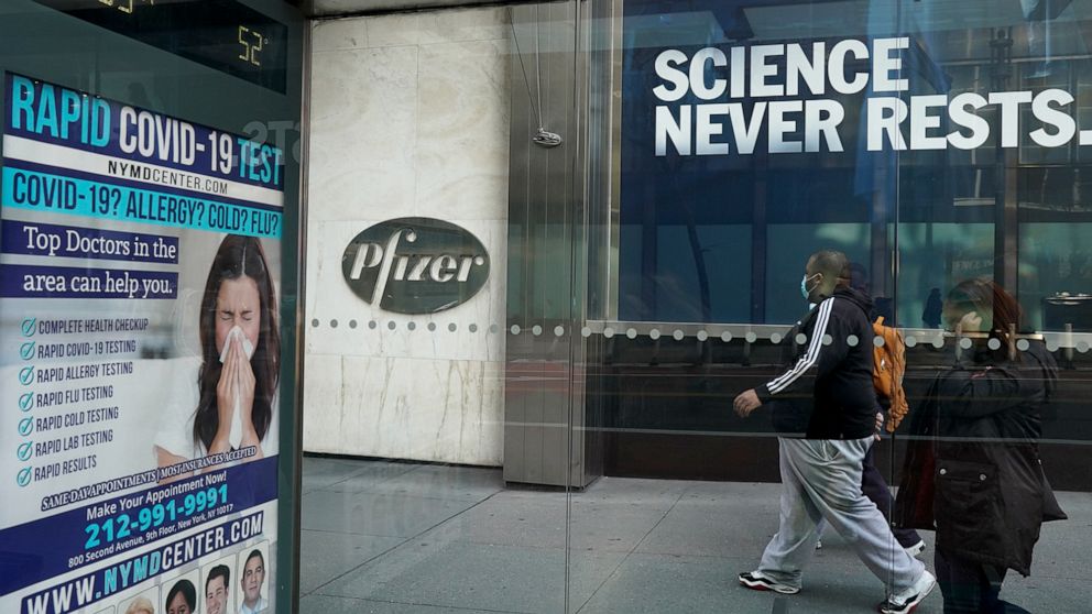 PHOTO:  A person wearing a protective face mask walks past the Pfizer Inc. headquarters in New York, Dec. 11, 2020.