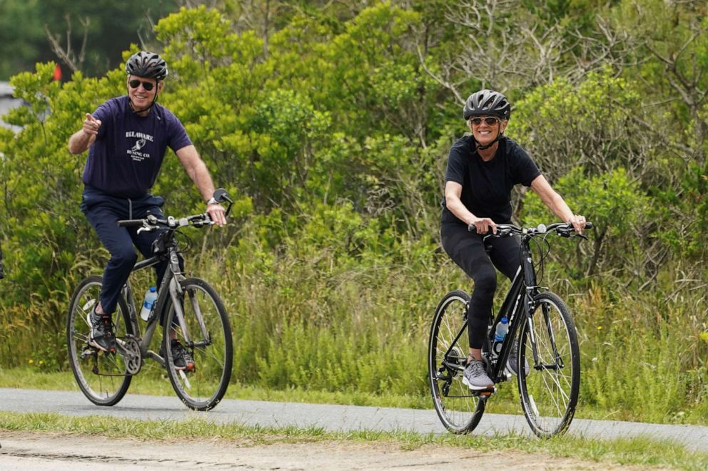 PHOTO: President Joe Biden acknowledges the news media as he follows first lady Jill Biden while biking at Cape Henlopen State Park in Rehoboth Beach, Del., June 3, 2021.