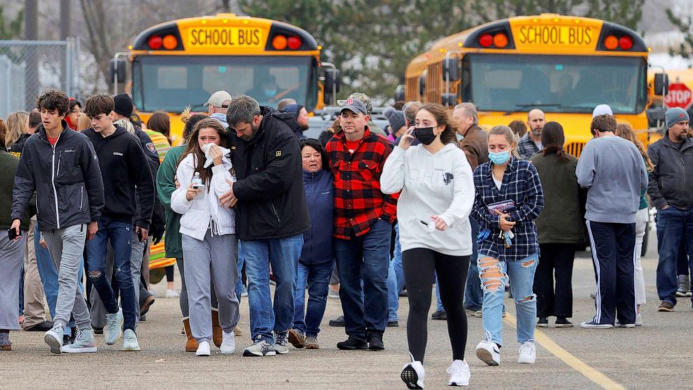 PHOTO: Parents walk away with their kids from the Meijer's parking lot where many students gathered following an active shooter situation at Oxford High School in Oxford, Mich., Nov. 30, 2021. 