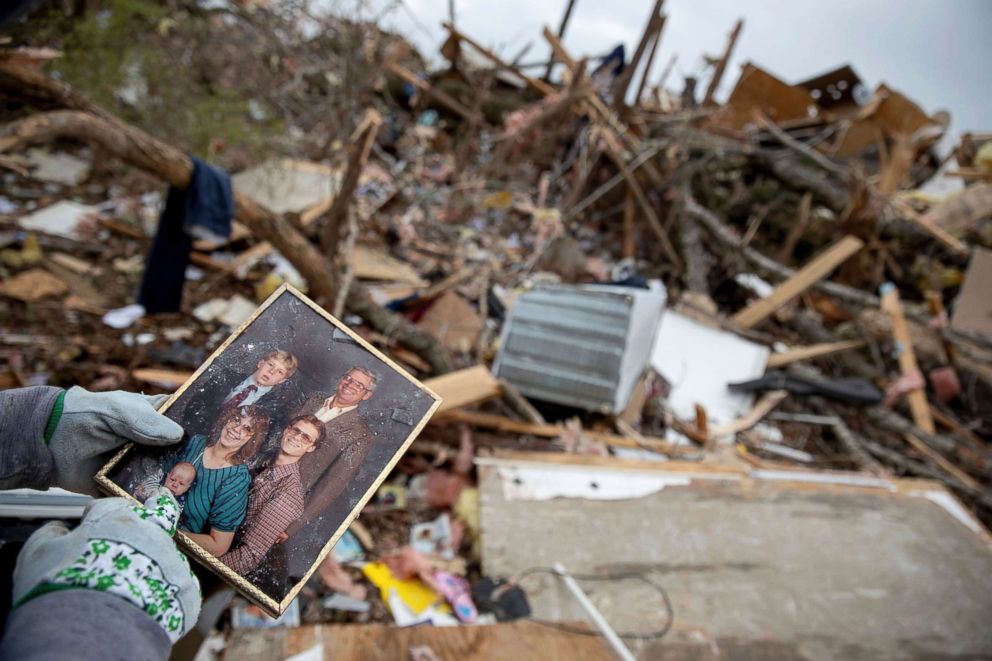 PHOTO: Danny Allen recovers a family photo while sifting through the debris of a friend's home destroyed by a tornado in Beauregard, Ala., March 4, 2019.