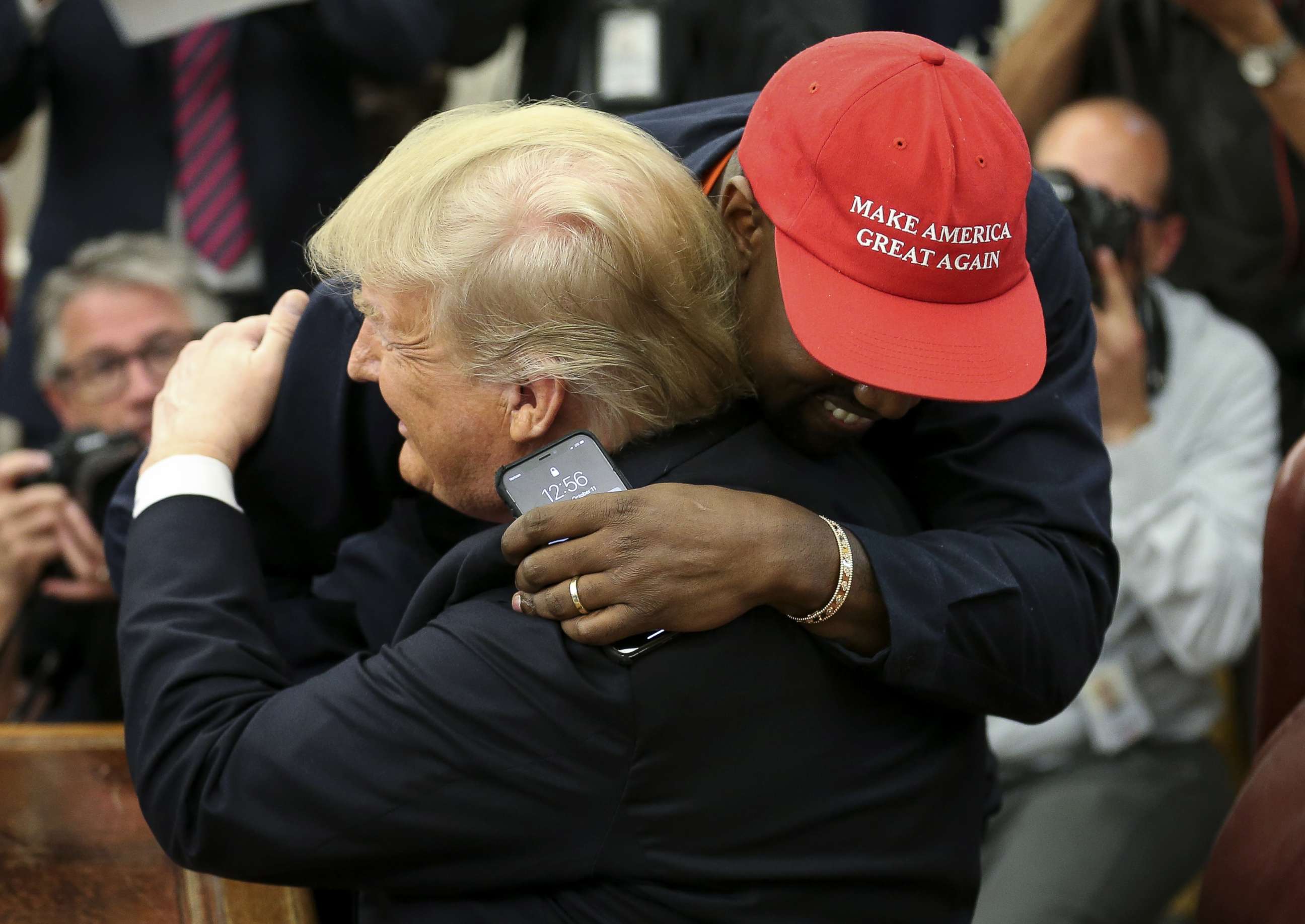 Kanye west smiling, dressed in the us president's suit in front of the  white house