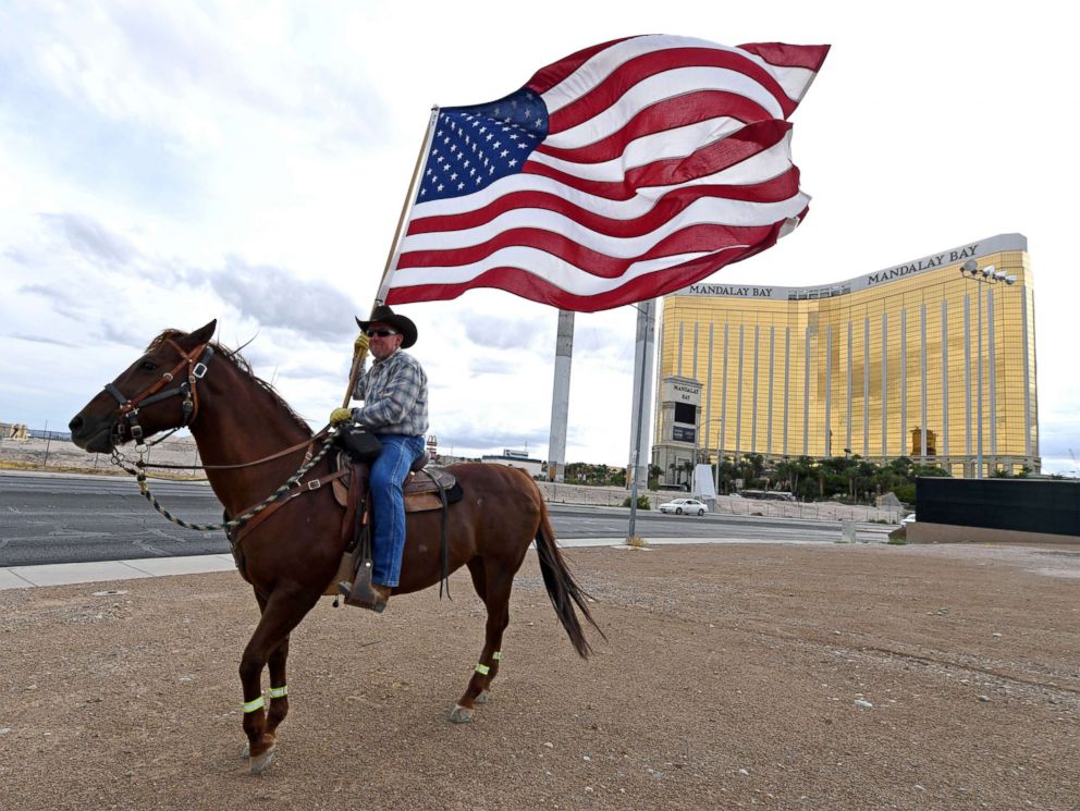 PHOTO: Rafael Sarabia holds an American flag as he rides his horse Red Sonja outside the Las Vegas Village across from Mandalay Bay Resort and Casino as a tribute to those killed in last year's massacre at the site, Oct. 1, 2018, in Las Vegas, Nevada.