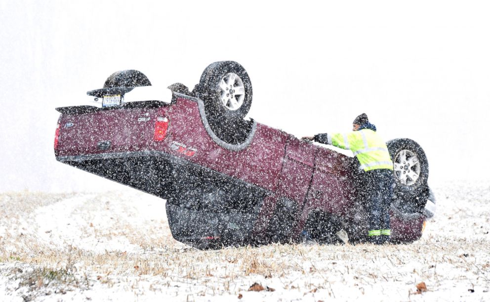 PHOTO: Snow falls as a man inspects an overturned pickup truck in a field on Blue Rock Road in Manor Township, Pa., Jan. 29, 2019.