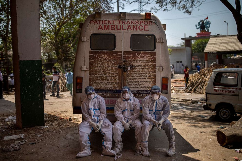 PHOTO: Exhausted workers sit on the rear step of an ambulance in New Delhi, April 24, 2021.