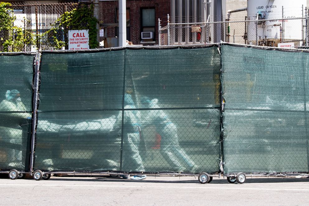 PHOTO: Hospital personnel behind a barricade move deceased individuals to the overflow morgue trailer outside The Brooklyn Hospital Center in New York, May 7, 2020.