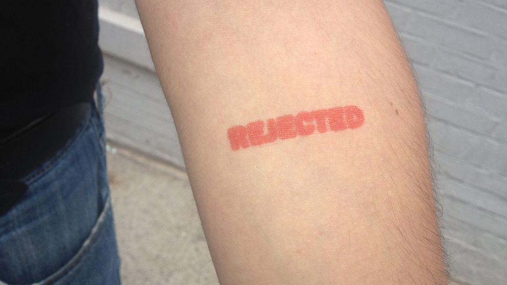 A protestor shows off his rejection stamp after trying to donate blood and admitting he is gay.
