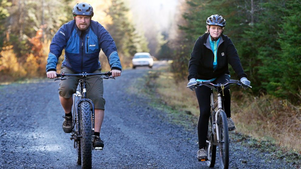 Nurse Kaci Hickox, right, and her boyfriend, Ted Wilbur are followed by a Maine State Trooper as they ride bikes on a trail near her home in Fort Kent, Maine, Oct. 30, 2014.