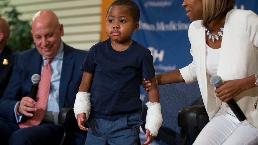 Double-hand transplant recipient, eight-year-old Zion Harvey, is accompanied by Dr. L. Scott Levin, left, and his mother Pattie Ray, right, on July 28, 2015 in Philadelphia.