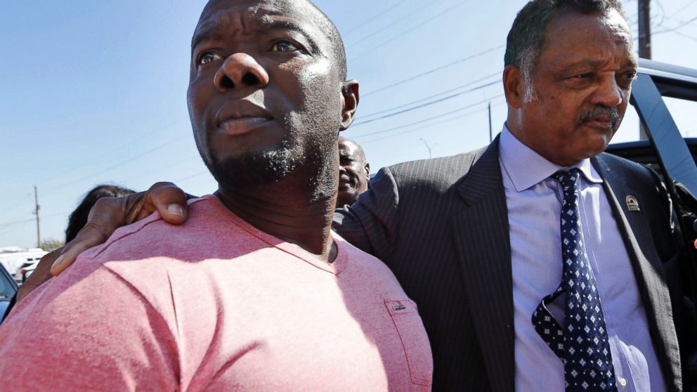 Joe Weeks, left, nephew of Ebola patient Thomas Eric Duncan, stands next to the Rev. Jesse Jackson as he finishes up speaking to reporters, Oct. 7, 2014, in Dallas.