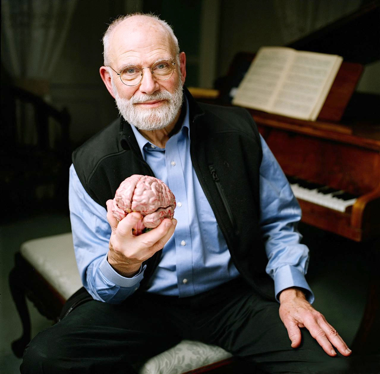 PHOTO: Neurologist Oliver Sacks poses at a piano while holding a model of a brain at the Chemistry Auditorium, University College London in London.