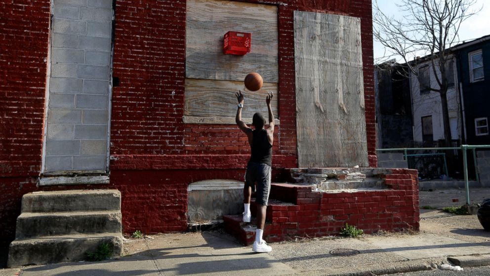 PHOTO: A boy shoots a basketball into a makeshift basket made from a milk crate and attached to a vacant row house in Baltimore, April 8, 2013. 