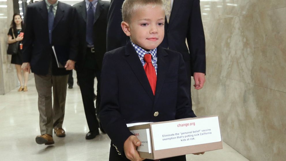 Leukemia survivor Rhett Krawitt, 7, carries a box of petitions representing more than 30,000 people supporting a measure requiring nearly all California school children to be vaccinated, to the governor's office at the Capitol in Sacramento, Calif. on June 24, 2015. 