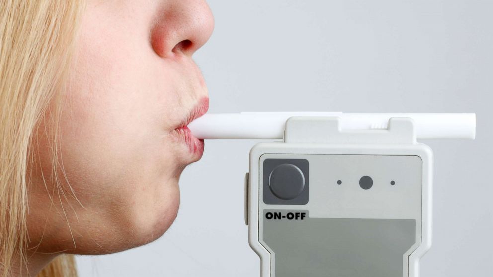 A woman blows on a police issue breathalyzer in an undated stock photo.