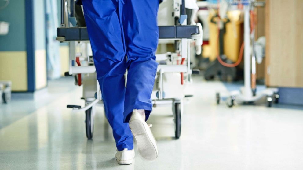 A medic runs with a gurney along a hospital corridor.