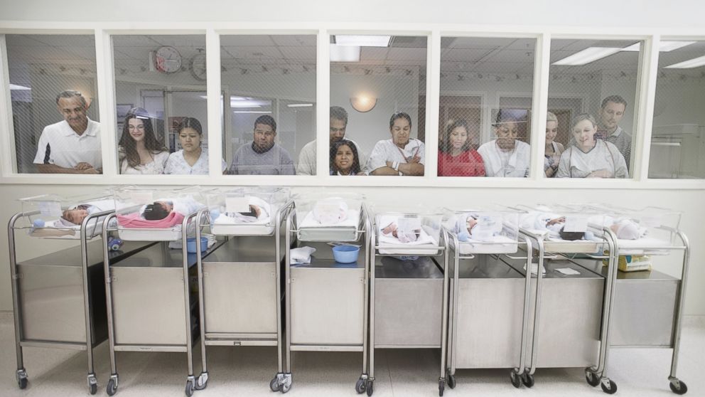 New parents watch their babies in the hospital nursery.