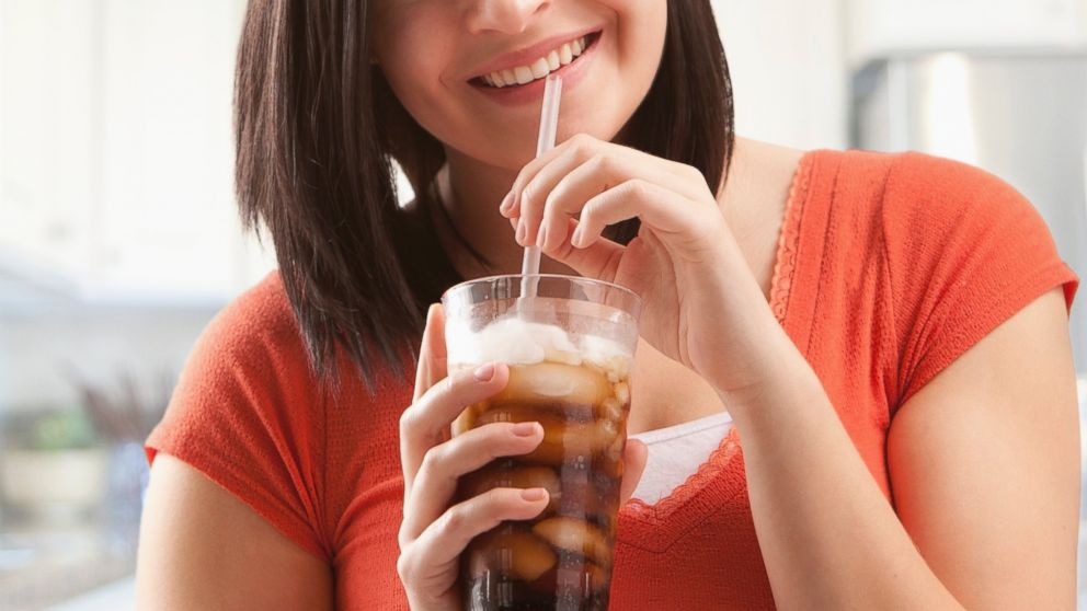 A woman is pictured drinking soda in this stock image. 