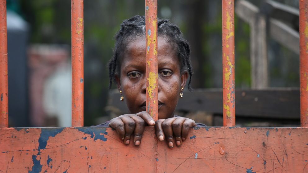 A West Point slum resident looks from behind closed gates on the second day of the government's Ebola quarantine on their neighborhood in Monrovia, Liberia, Aug. 21, 2014.