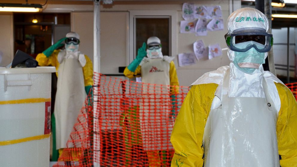 Health workers wearing protective gear gesture at the Nongo ebola treatment centre in Conakry, Guinea, Aug. 21, 2015.