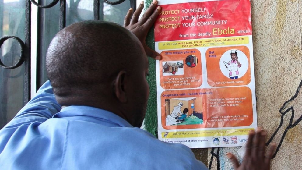 PHOTO: A nurse sets an information sign about Ebola on a wall of a public health center