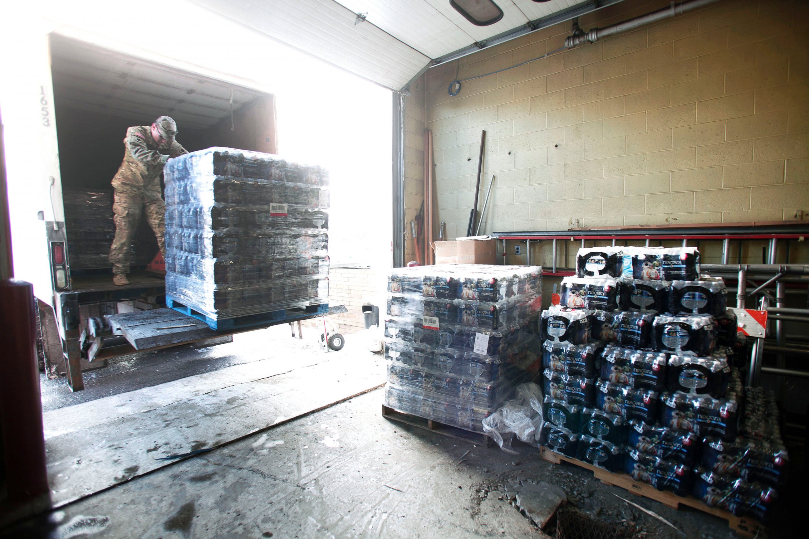 PHOTO: Michigan National Guard Staff Sergeant William Phillips of Birch Run, Michigan, helps unload pallets of bottled water at a Flint Fire Station, Jan. 13, 2016, in Flint, Michigan.